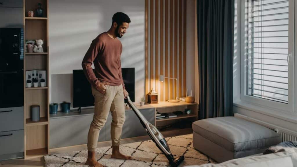 Man vacuuming with earbuds in and a smile on his face