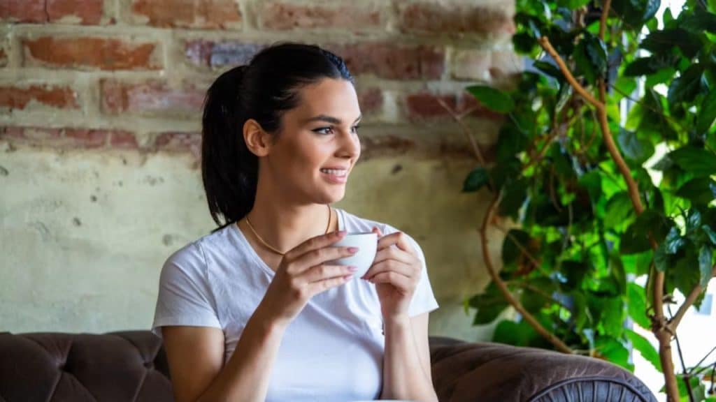 Woman enjoying alone time at a coffee shop while smiling to herself.