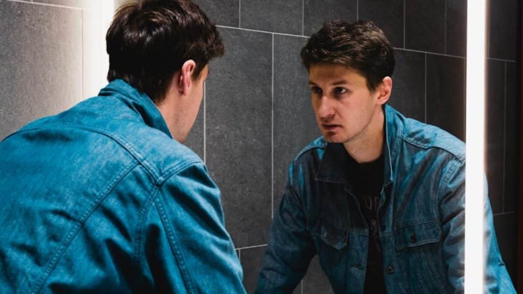 Man staring at himself in the mirror, deep in thought.