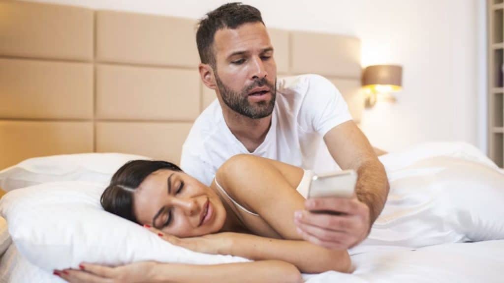 Man sneaking a look at his partner’s phone at night.