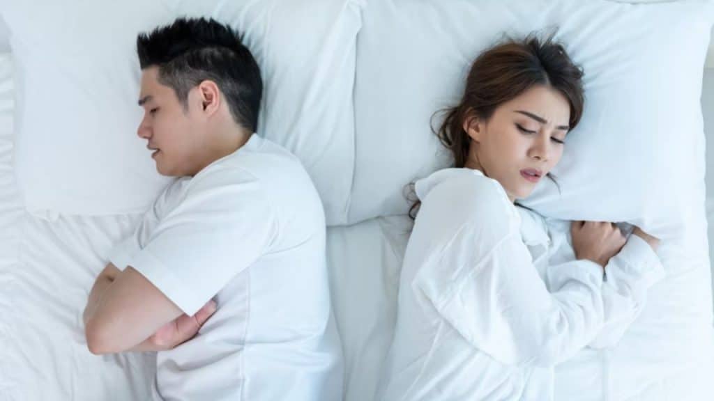 Woman lying awake in bed beside partner.