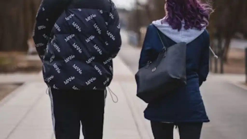 Man walking ahead of partner on a sidewalk.