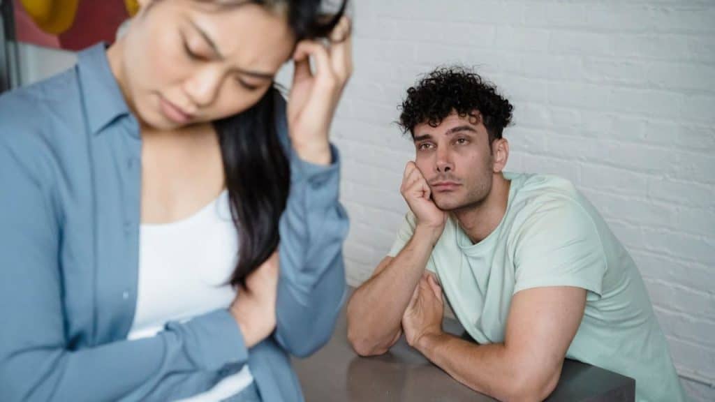 Woman feeling neglected while sitting beside her partner.