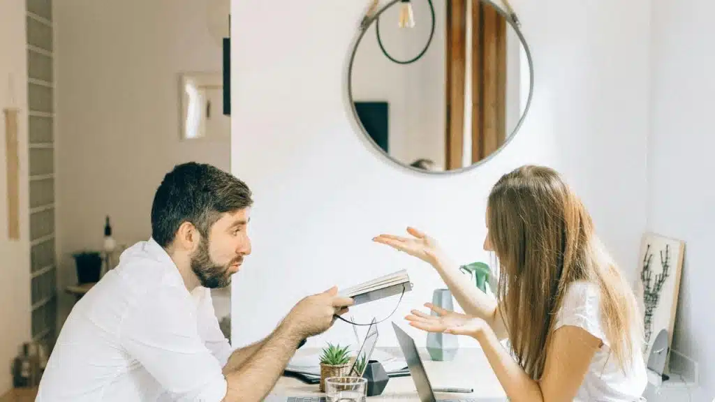 A woman speaking and feeling ignored while her partner sits and reads a book.
