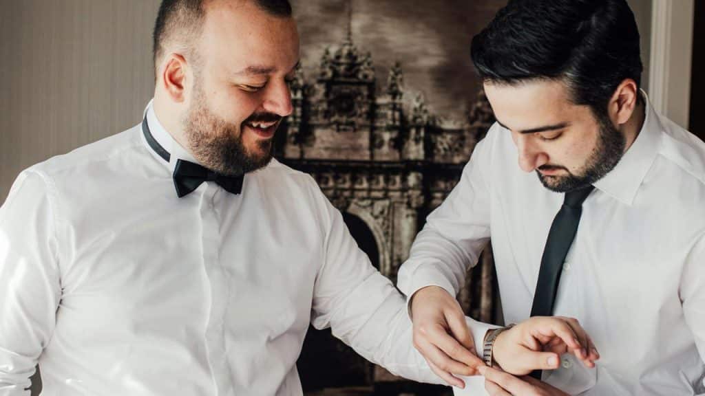 A man helping another adjust his cufflinks.