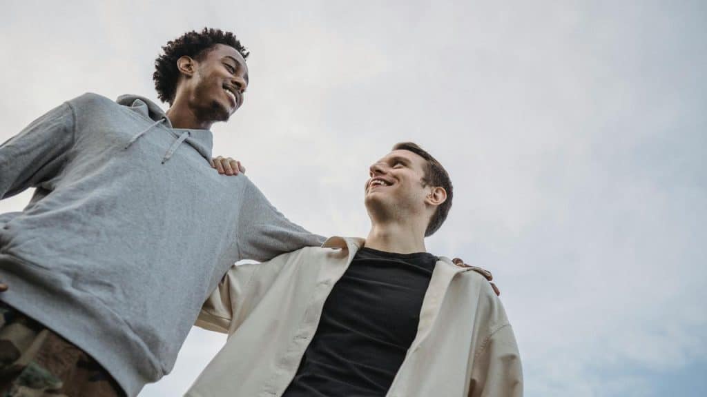 A pair of friends with arms around each other, smiling.