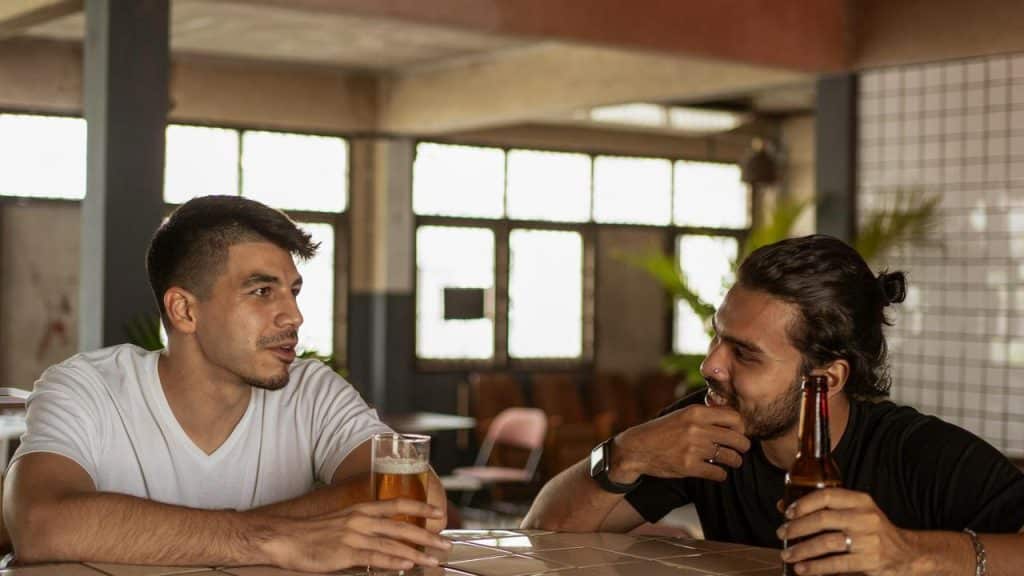 A pair of men chatting over beers at a bar.