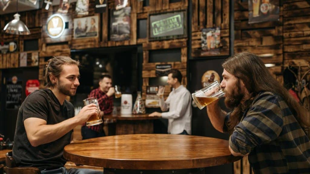 A group of men drinking beer and talking at a rustic bar..