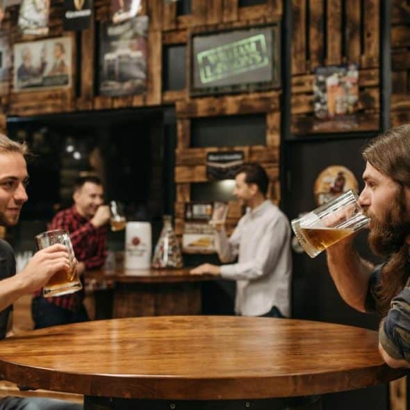 A group of men drinking beer and talking at a rustic bar..