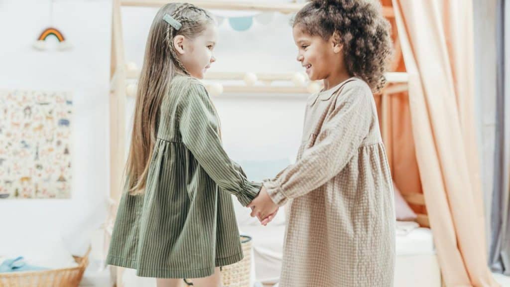 A pair of girls holding hands and smiling.