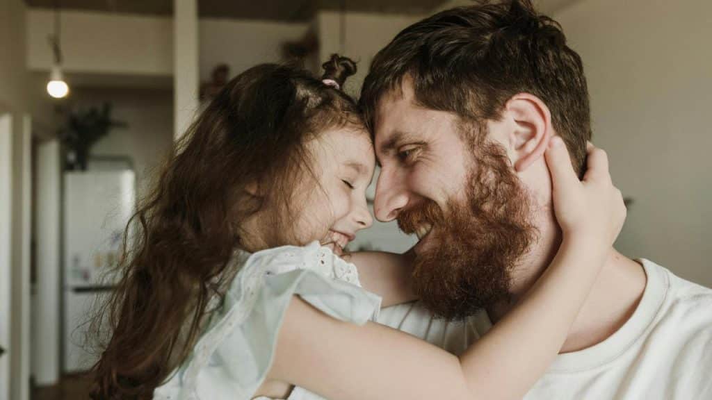 A father and daughter smiling with their foreheads touching.
