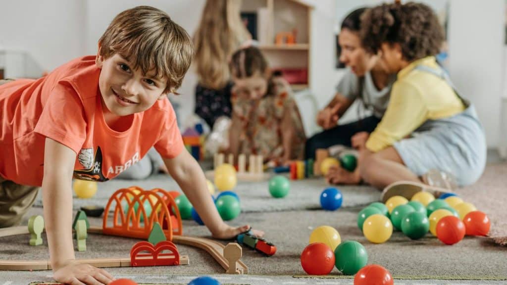 A boy smiling while playing with toys in a playroom.
