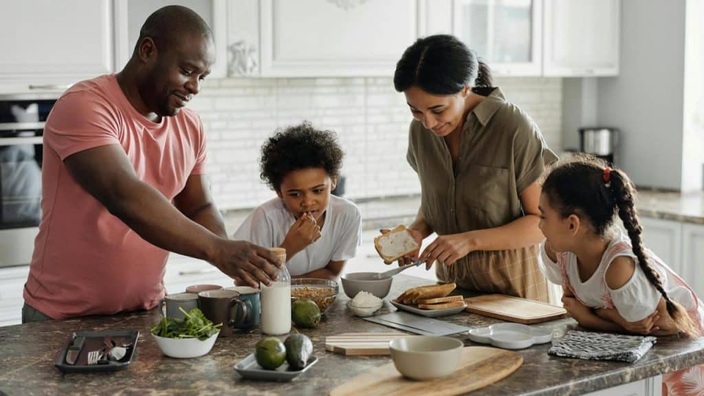 A family of four preparing breakfast together in a modern kitchen.