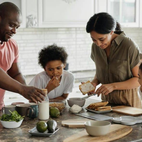 A family of four preparing breakfast together in a modern kitchen.