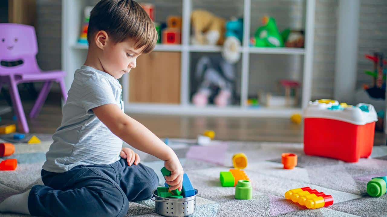 A boy playing with blocks on the floor.