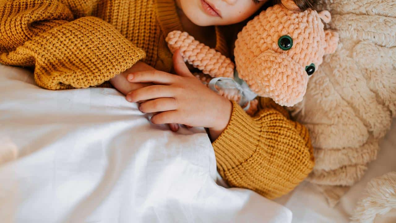 A child cuddling a stuffed animal in bed.