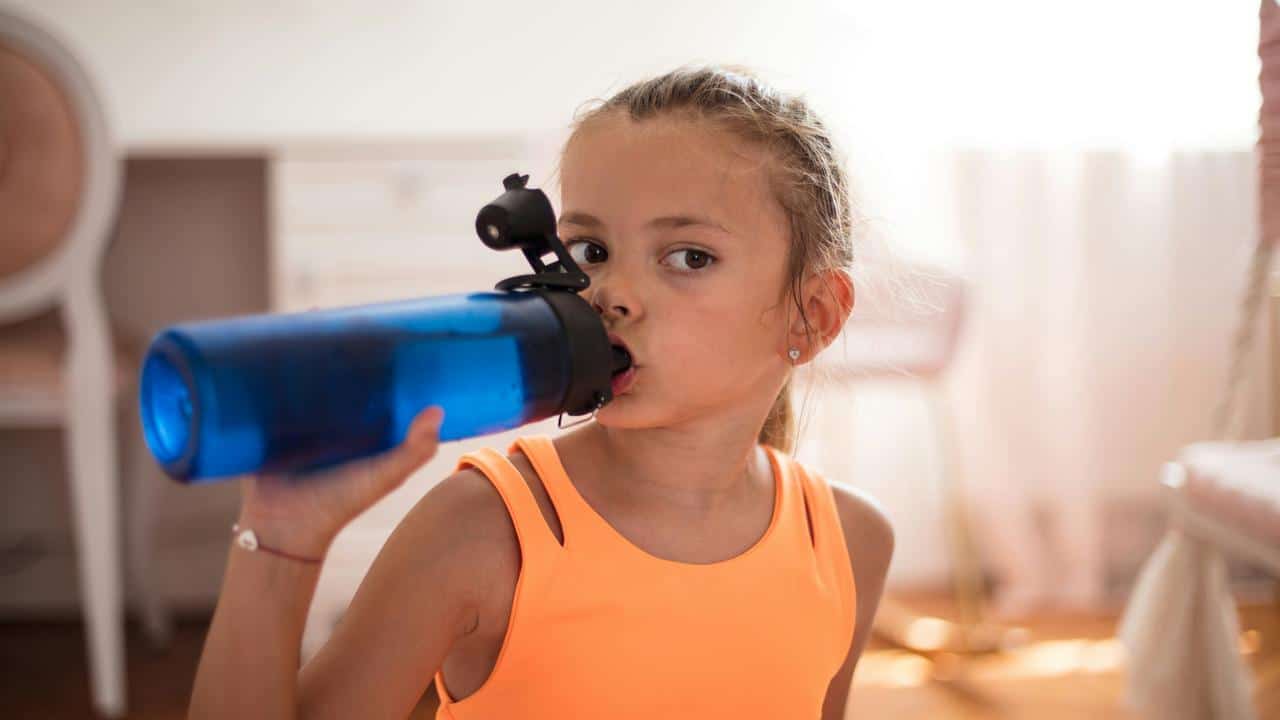 A girl drinking from a blue water bottle.