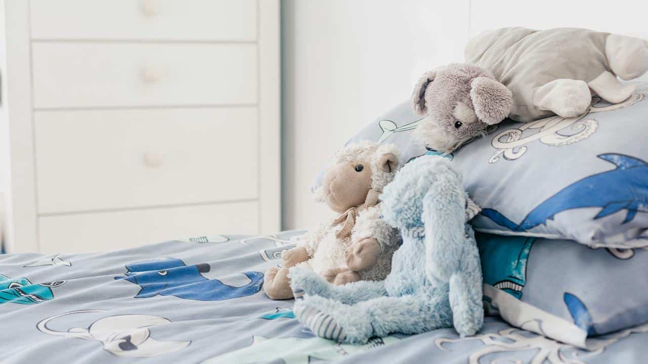 A group of stuffed animals on a child’s bed.