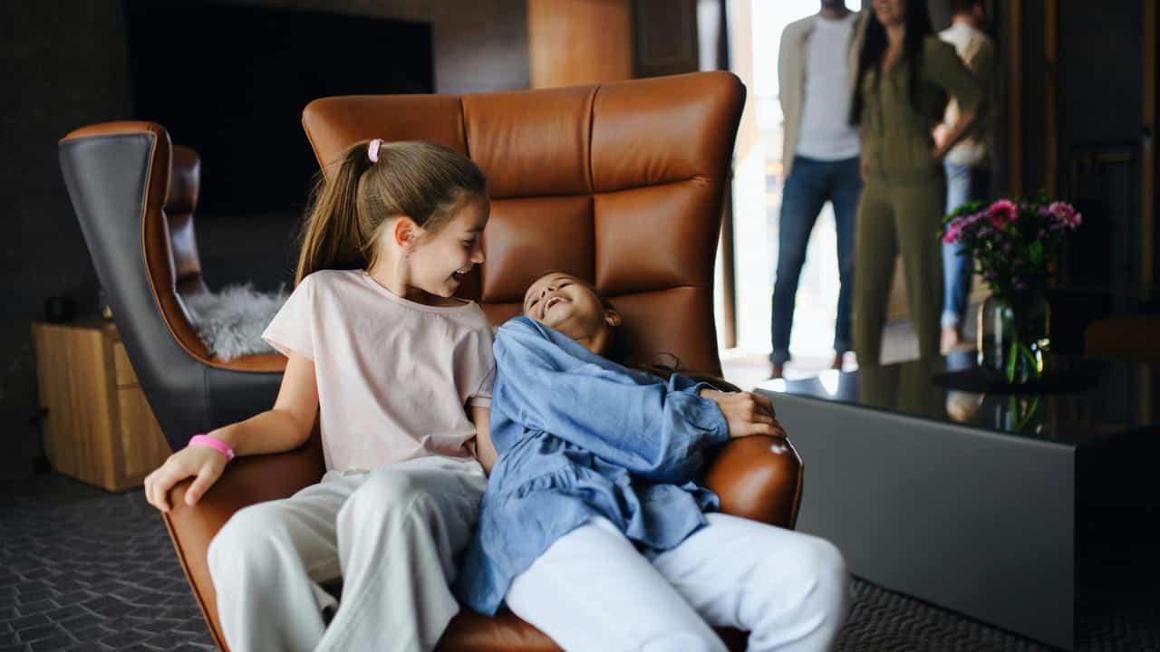 A pair of girls laughing on a large chair.