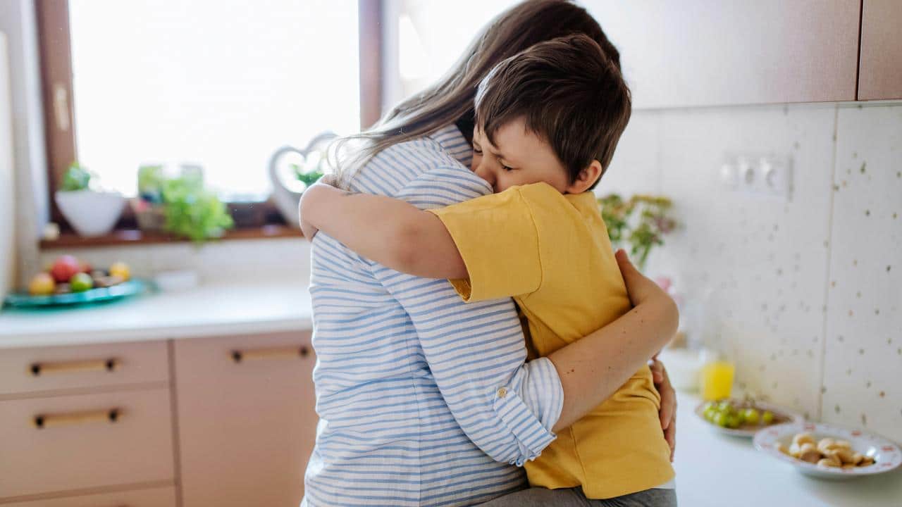 A child hugging an adult in a kitchen.