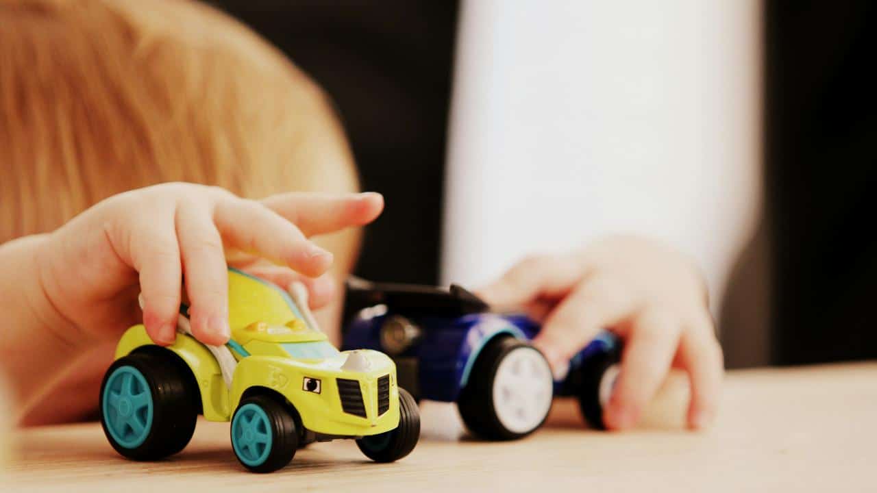 A child playing with toy cars on a table.