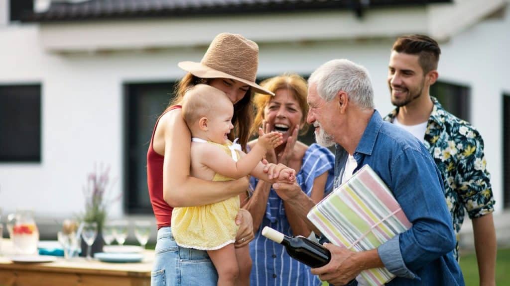 A multi-generational family happily celebrates a special occasion outdoors.