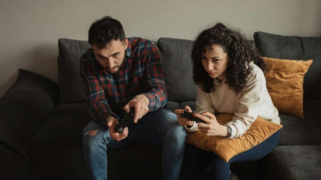 A focused man and a woman playing video games on a couch.