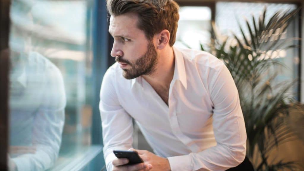 Anxious man checking phone frequently, craving partner's validation