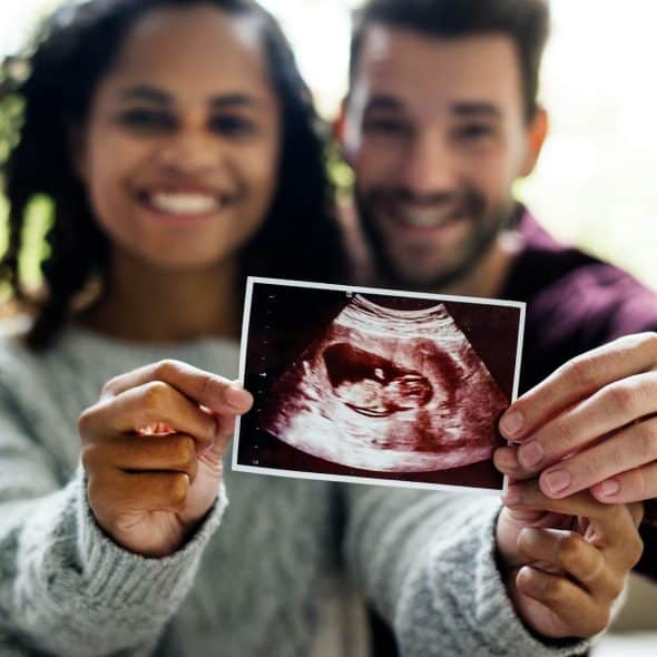 A man and woman holding a sonogram