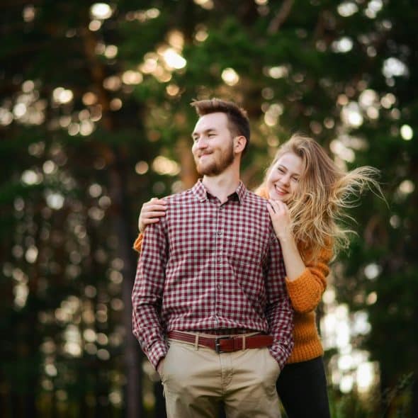 A woman hugging a man from behind.