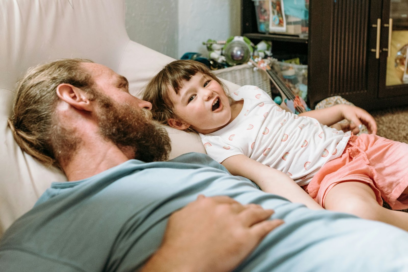 A man laying on a couch with his daughter.