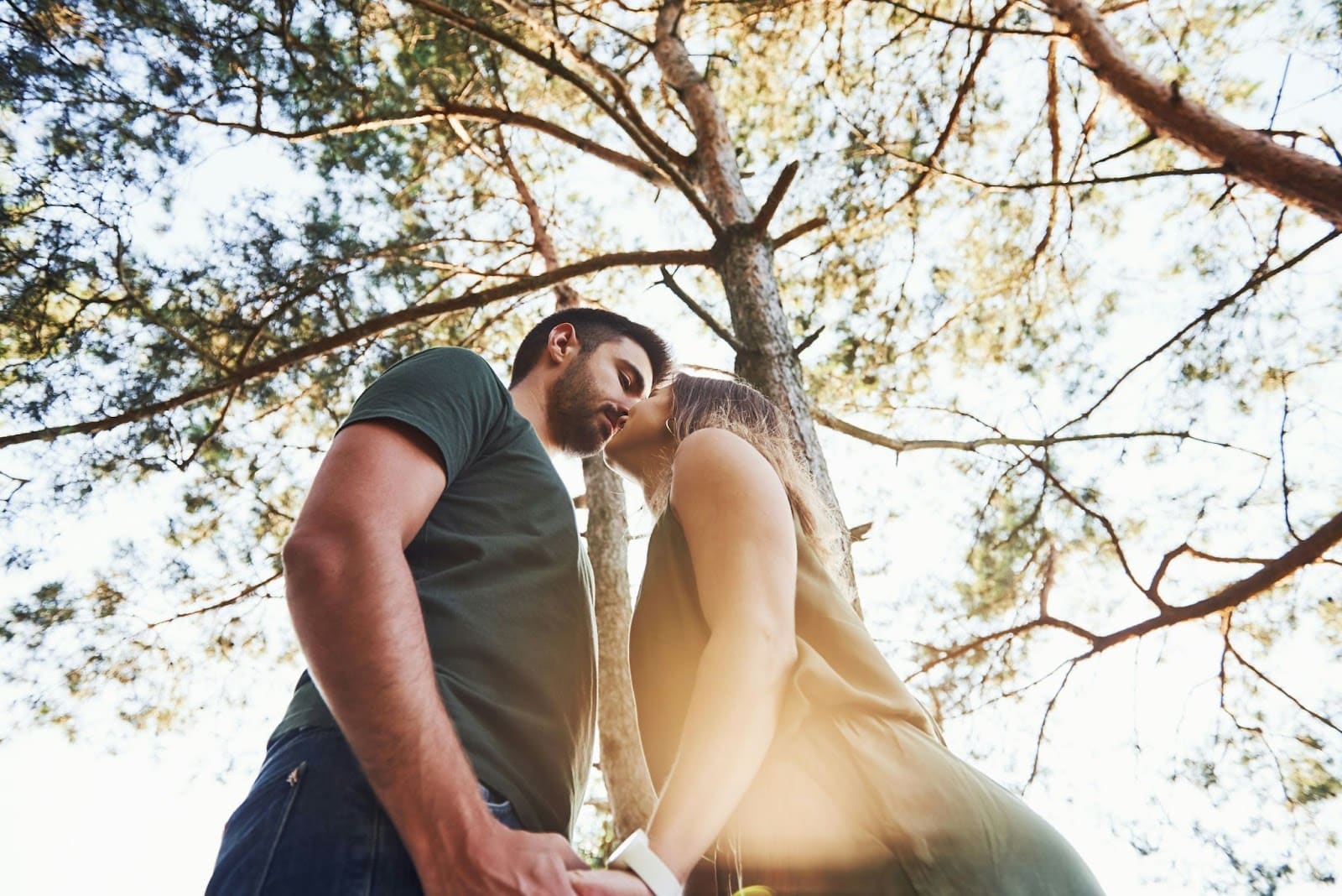 A man and woman kissing under the tree.