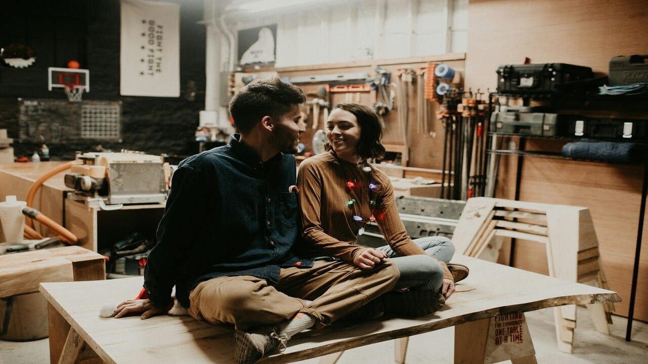 A couple sitting at a furniture workshop.