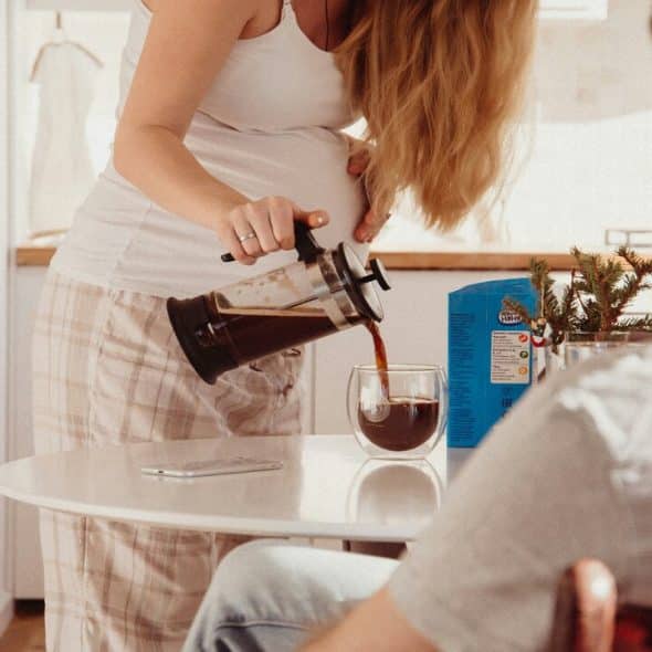A woman pouring coffee while her husband watches.