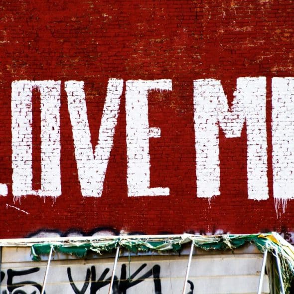 “Love me” painted on a red wall.