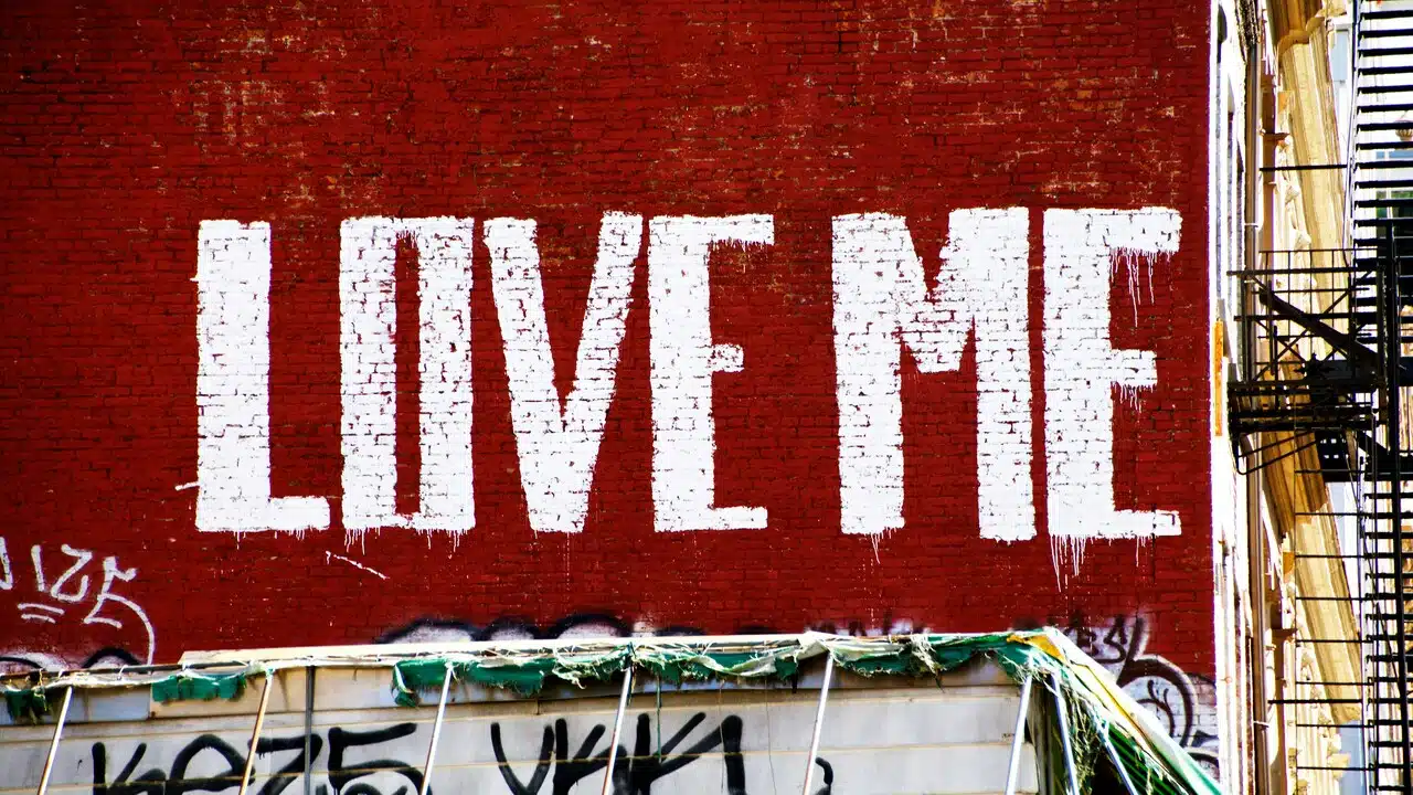 “Love me” painted on a red wall.