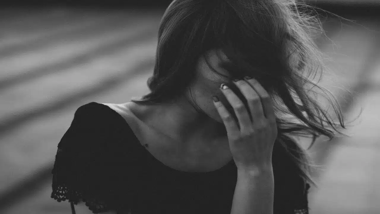 A woman covering her face with her hand.