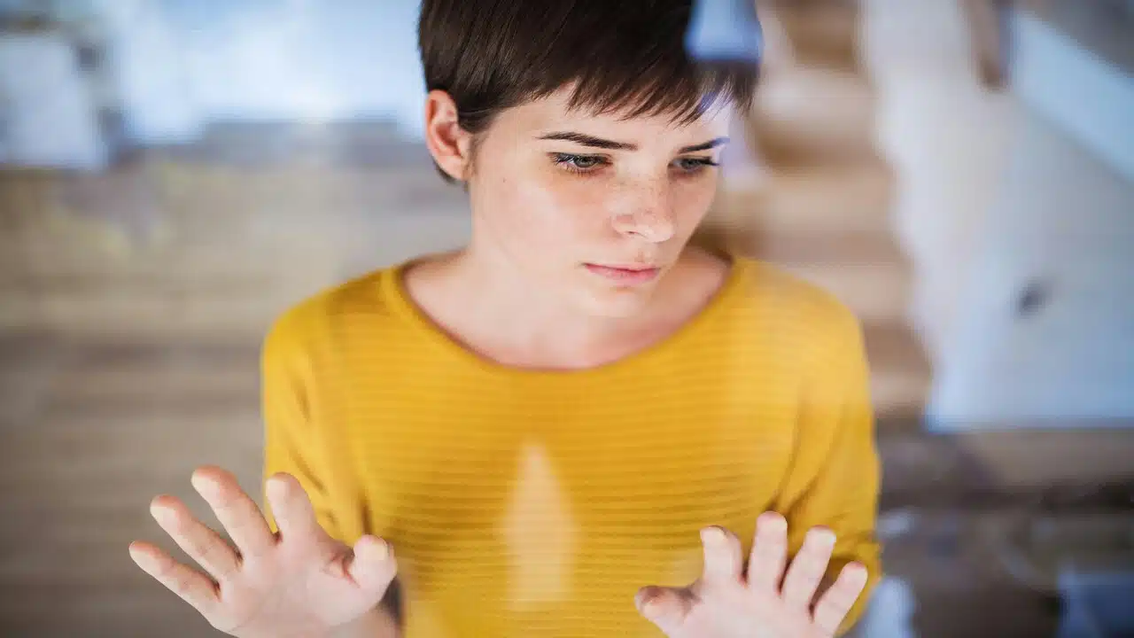 A worried woman in front of a window.
