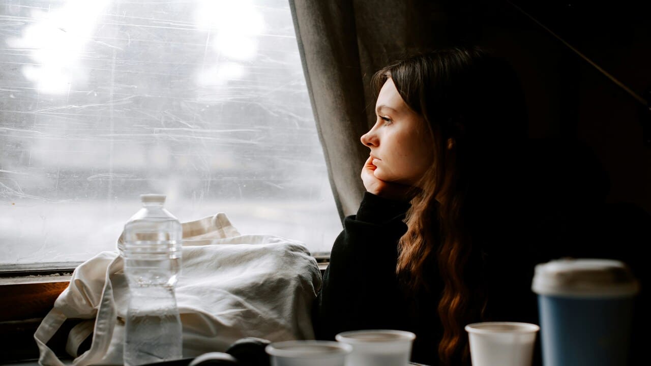 A woman looking sad while looking out the window.