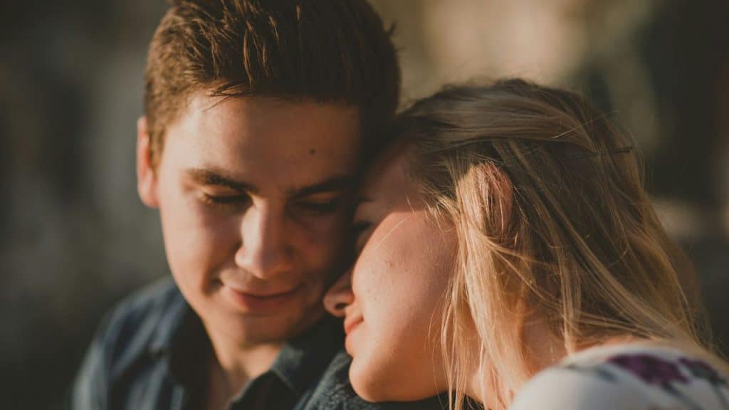 A loving portrait of a young couple, with the woman leaning her head on the man's shoulder.