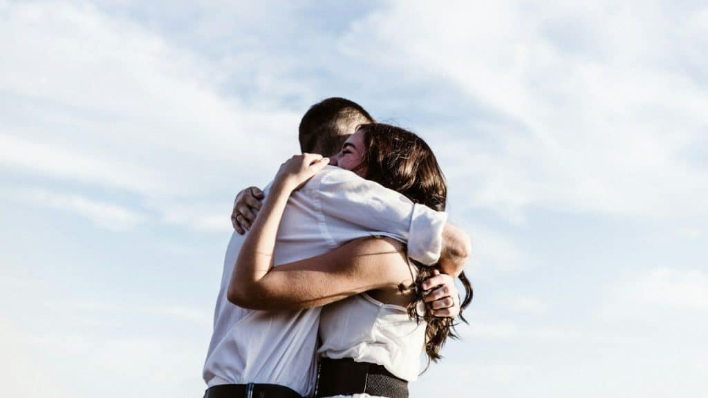 A man and a woman embrace with their arms around each other.