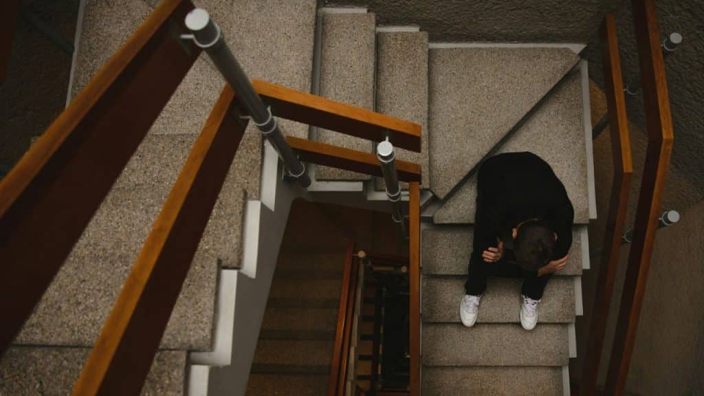 A high-angle view of a sad person sitting alone on a concrete staircase.