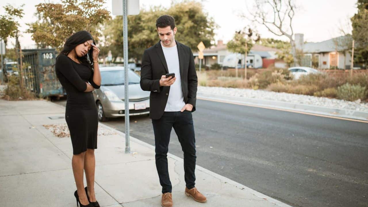  ALT Text: Man ignoring partner by prioritizing his phone during quality time.