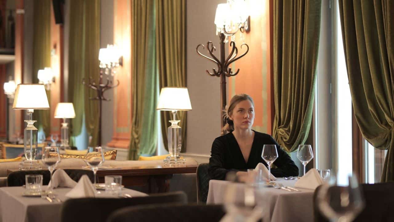 Woman waiting alone at a restaurant while checking the time.