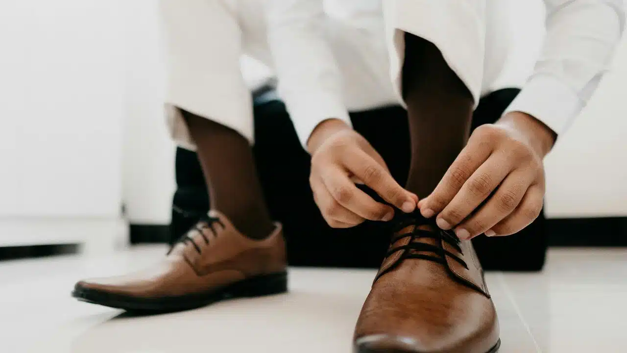A man tying brown dress shoes.