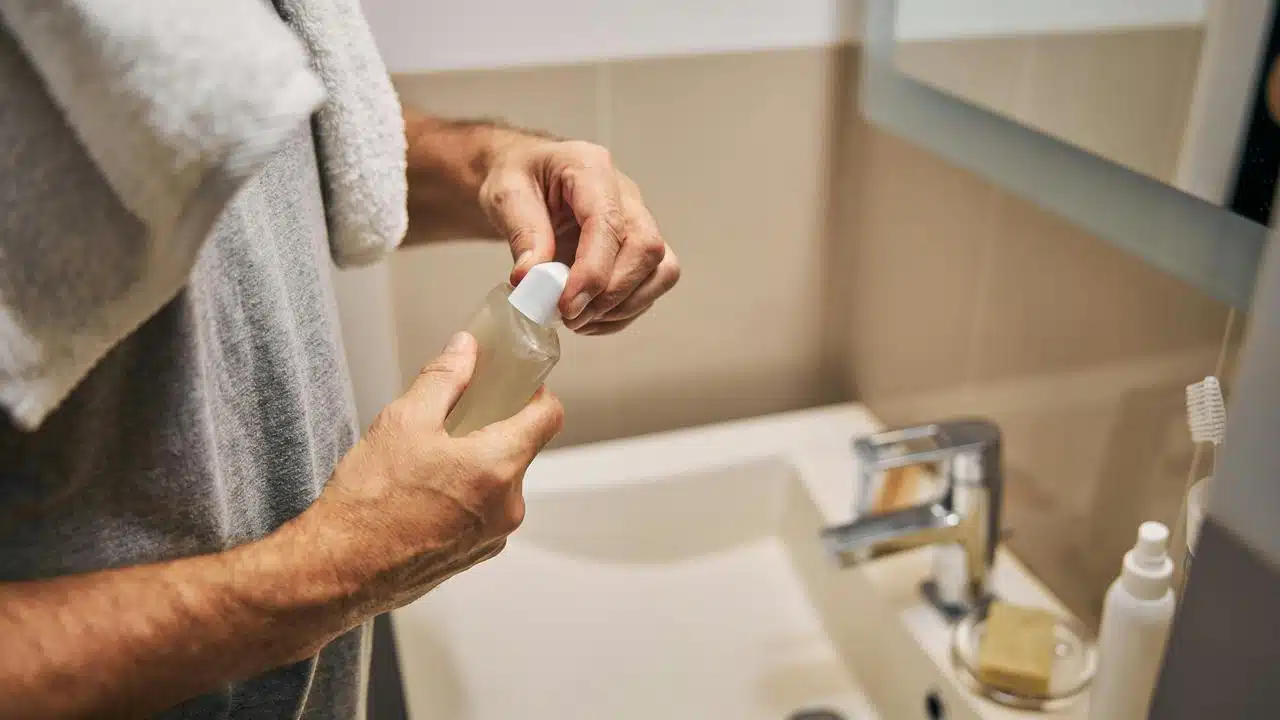A man opening a bottle in the bathroom.