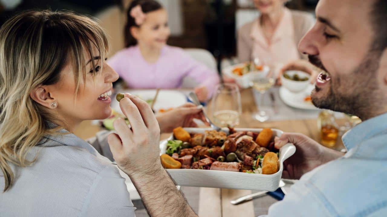 A couple sharing food at a family dinner.