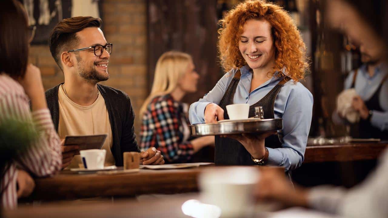A server handing coffee to a smiling customer.