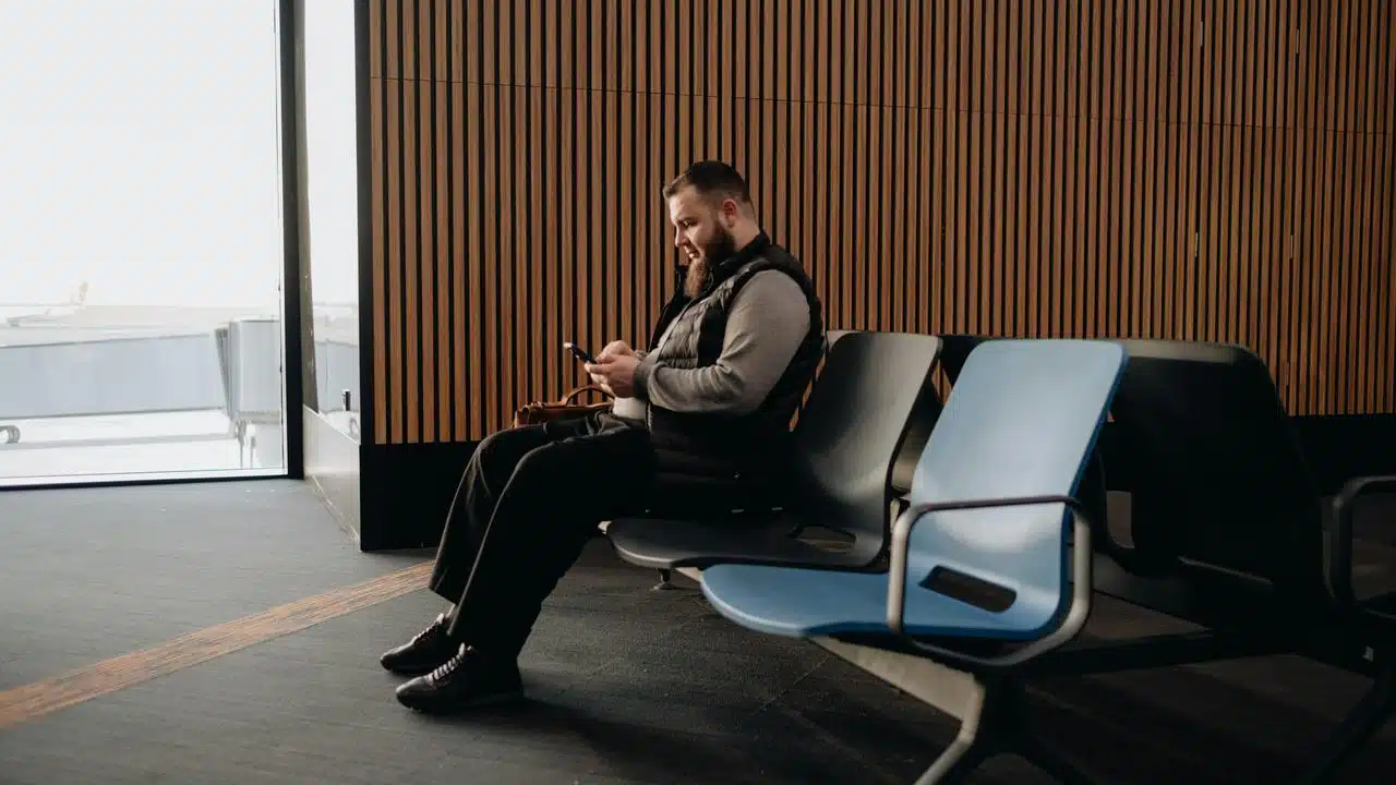 A man sitting in an airport using his phone.