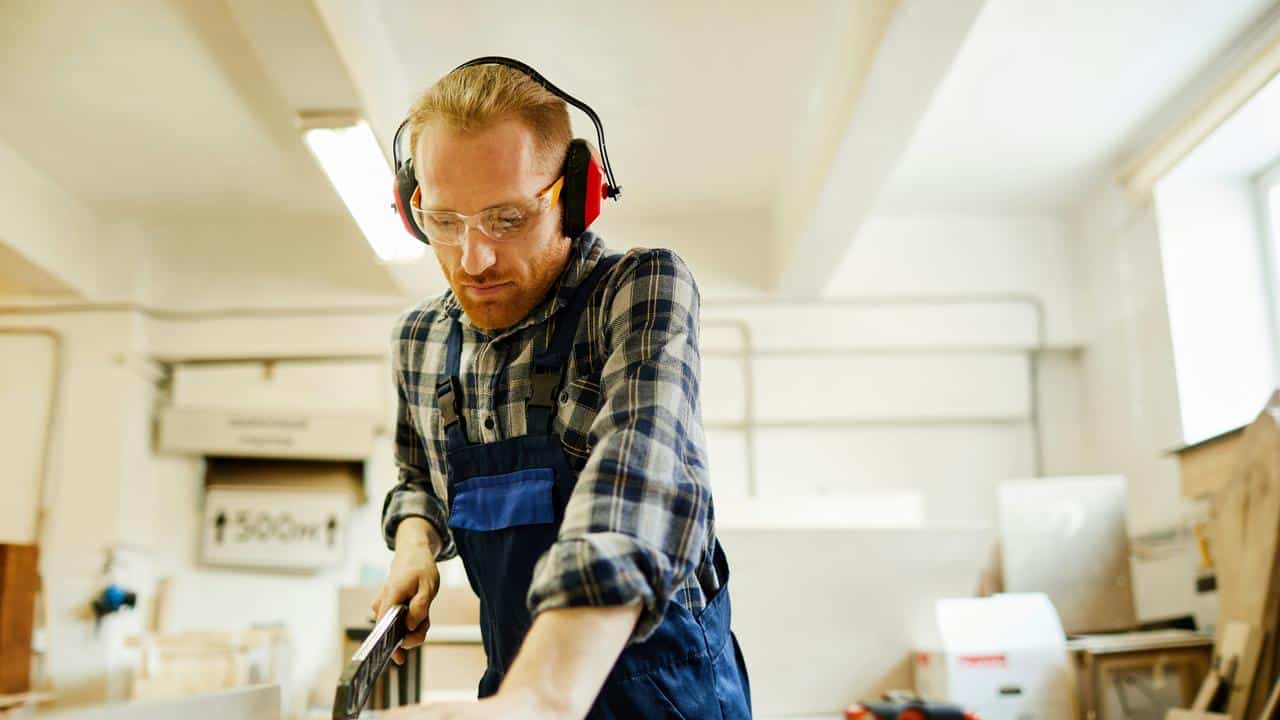 A man working with protective gear in a workshop.